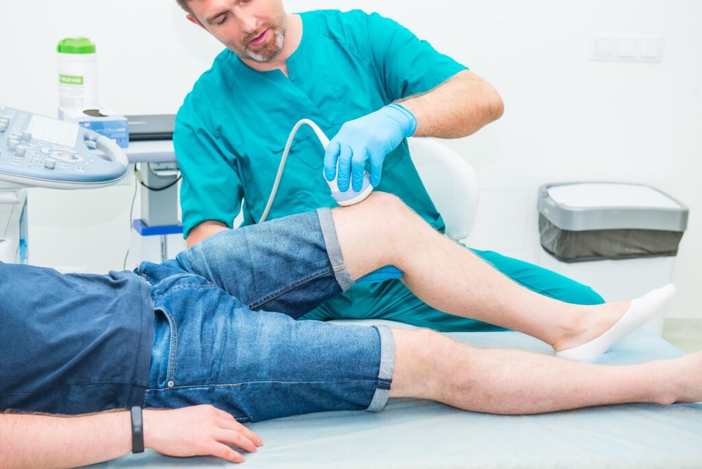 Orthopedist doctor conducting ultrasound examination of patient's knee in clinic