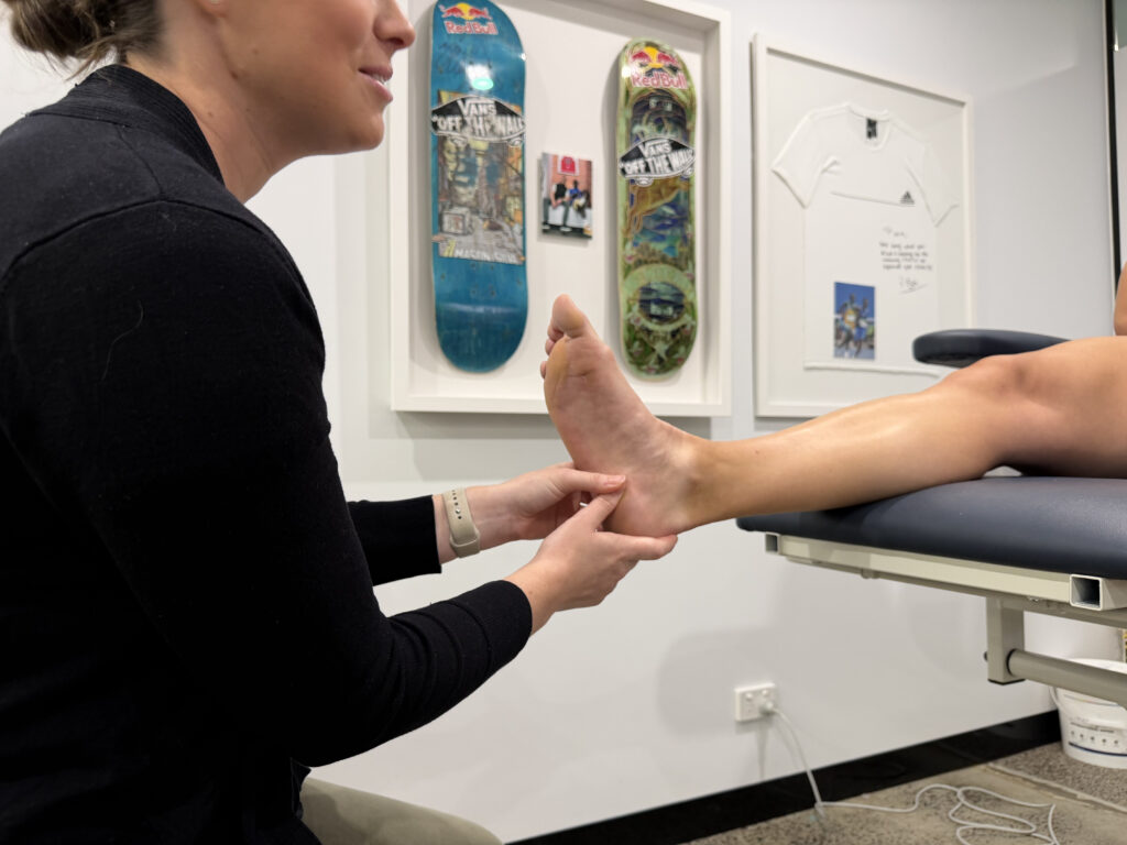Podiatrist pressing the focal heel pain area during plantar fasciitis assessment