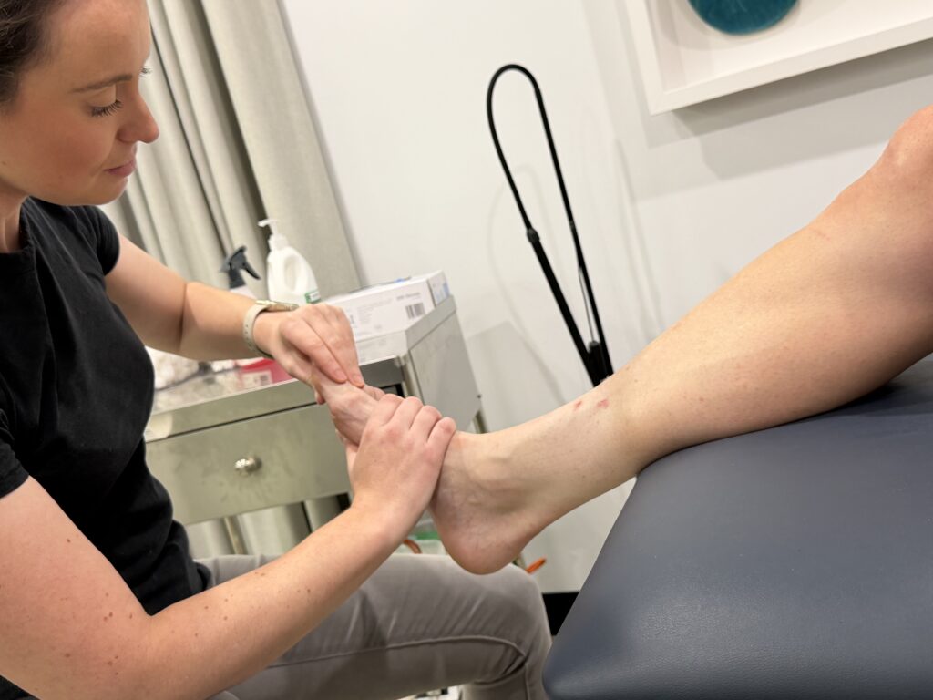 Podiatrist applying joint mobilisation techniques for big toe arthritis to assess stiffness and mobility.