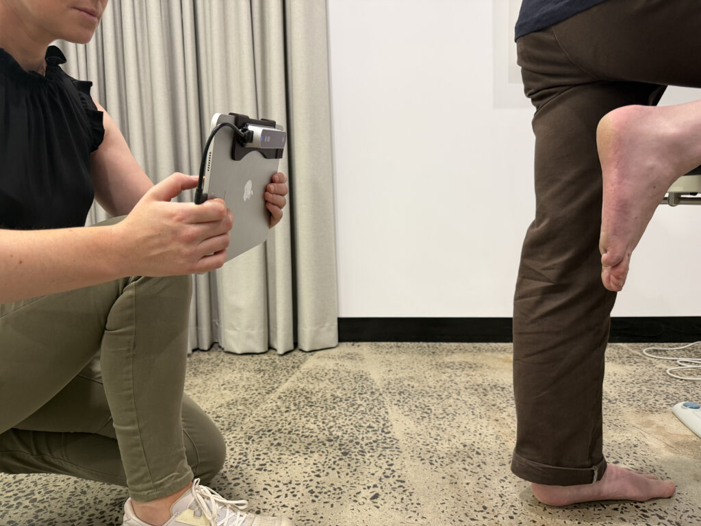 Podiatrist fitting custom orthotics using standing foot scan assessment