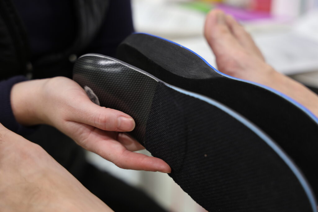 Custom orthotic being fitted into a shoe by a Melbourne podiatrist